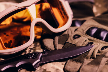 Wall Mural - Tactical military gloves, helmet, glasses and knife on the khaki camouflage uniform. Soldier ammunition.