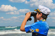 Boy with binocularsA boy with binoculars watches a military boat