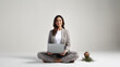 © Studio Nova - Woman sitting cross-legged on the floor, smiling and looking at a laptop placed on her lap against a plain white background.
