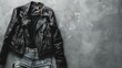 A black leather jacket hangs dramatically on a weathered wall