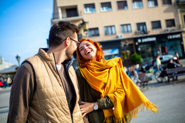 Wall Mural - Smiling couple enjoying on vacation, young tourist having fun walking and exploring city street during the day.