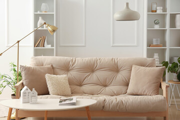 Interior of light living room with cozy white sofa and coffee table