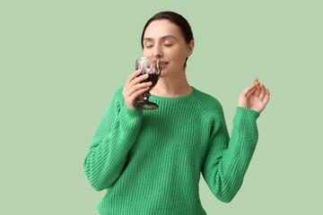 Poster - Beautiful young woman with glass of red wine on green background