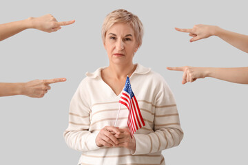 Wall Mural - People pointing at mature woman with USA flag on light background. Accusation concept