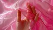A close-up of a woman's hand holding up a piece of pink fabric. Suitable for fashion or DIY projects