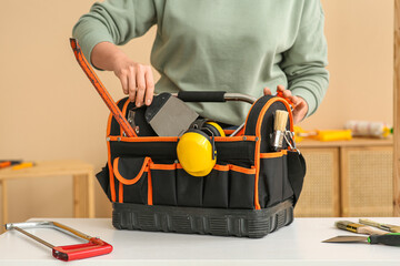 Female worker with tools bag in room