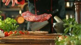 Fototapeta Lawenda - Chef Throwing Raw Beef Steak on Wooden Cutting Board.