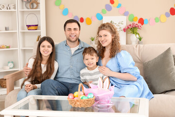 Wall Mural - Happy family sitting at table with Easter eggs at home