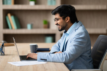 Aufkleber - Side view of Indian businessman browsing on laptop in workspace