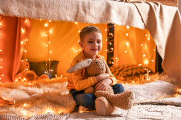 Canvas Print - Boy playing with toy bunny in play tent at home