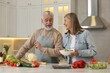 © New Africa - Happy senior couple cooking together in kitchen