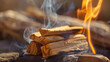 Closeup of a lit bundle of palo santo wood releasing fragrant smoke during a cleansing ritual.