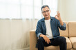 © Chanakon - Handsome asian mature old man sitting on sofa couch in living room at home. Happy Portrait of cheerful smiling senior asian man relax in the house. Mature People and lifestyle