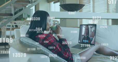Poster - Multiple increasing numbers falling against woman having a image call on laptop at home