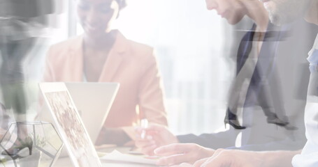 Poster - Image of diverse colleagues using laptops in office over sped up commuters walking