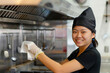 Happy Asian Chef Wiping Down Stainless Steel Kitchen Hood, Professional Cleanliness in Cuisine
