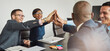 © Flamingo Images - Group of happy successful business people smiling and high fiving each other during a meeting in an office. Businessmen and women showing teamwork, collaboration in a diverse workplace.