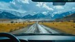 An aerial view of the landscape through the windshield of a car going across a meadow to high rocky mountains in different seasons with varying weather. The “natural landscape” is viewed from inside