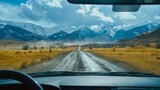 Fototapeta  - An aerial view of the landscape through the windshield of a car going across a meadow to high rocky mountains in different seasons with varying weather. The “natural landscape” is viewed from inside
