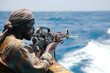 Young Somali pirate in boat with firearm in hands. African man eyes sharp and vigilant scanning open waters ahead for signs of target
