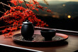 Traditional tea ceremony setup with a black pot and cup, complemented by fiery red leaves