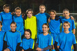 © PoppyPix - medium shot of soccer player girls in blue uniforms huddling each other for a team photo. High quality photo