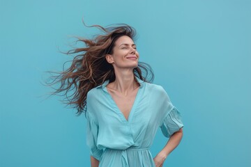 A woman with long hair is smiling and wearing a blue dress