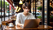 © anmitsu - Beautiful and handsome young man using a laptop in a cafe. He is a working male freelancer. Freelance work, businessman concept