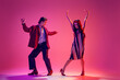 © master1305 - Young man and woman in stylish clothes dancing retro dance, boogie woogie against pink background in neon light. Concept of hobby, dance class, party, 50s, 60s culture, youth