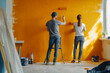 © valentyn640 - Man and woman are painting orange wall together.