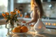 White essential oil diffuser on the table on light color kitchen, nearby orange and flowers, behind out of focus stay woman, copy space for text. Concept aromatherapy and relaxing. Air freshener