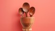 Wooden spoons in a cup resting on a bright pink background
