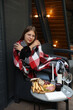© Anhelina  - the girl is sitting covered with a blanket on the terrace. rest and relaxation. red wine, glasses and candles are on the table. autumn mood romantic dinner. drink wine on the terrace. cabin house.