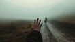 a hand reaching out to the side of a road with a person walking on it