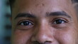 Macro close-up of South American latin young man eyes staring at camera smiling. Happy expression of a Brazilian 20s person