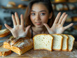 Gluten allergy, asian young woman hand push out, refusing to eat white bread slice on chopping board in food meal at home, girl having a stomach ache. Gluten intolerant and Gluten free diet concept