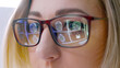 © wedmoments.stock - Close-up of glasses and reflection of MRI scan panorama. Close-up of a woman wearing glasses looking at a laptop, with multiple MRI scans of her head visible in the reflection of the glasses.