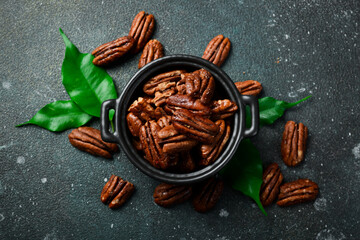 Wall Mural - Caramelized pecans in a bowl. Top view. On a dark background.