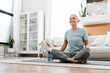 © InsideCreativeHouse - Middle-aged woman doing yoga at home on fitness mat. Caucasian mature female athlete meditating in lotus position, doing training indoors on the floor
