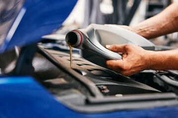 Close-up of car mechanic changing oil in car engine