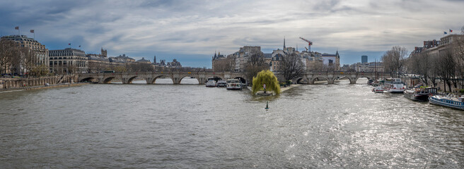 Wall Mural - Paris, France - 03 08 2024: The quays of the Seine. View of Pont Neuf with barges, Samaritaine building, Notre Dame Cathedral and the bell tower of the Sainte-Chapelle in the background.