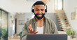 © Wesley/peopleimages.com - Man, headset and talking in home on video call, live streaming and presentation in online conference. Remote work, laptop or virtual assistant for contact centre or customer support at kitchen table
