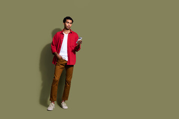 Wall Mural - Full length photo of cool funky guy wear red shirt chatting modern gadget empty space isolated khaki color background