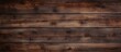 A closeup of a brown hardwood rectangular table plank with a wood stain finish. The beautiful wood grain pattern pops against a blurred background
