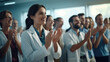 © MP Studio - A group of healthcare professionals in lab coats clapping and smiling, seemingly celebrating or acknowledging a success or achievement.