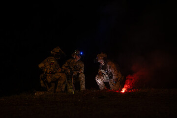 Wall Mural - Group of soldiers in camouflage uniforms hold weapons with patrol missions at night