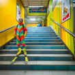 Smiling man skiing down the subway stairs, ski descent in the tube stairway, a person in colorful outfit eager to leave on vacation, fun guy who can't wait to go on holiday, crazy skier in the tube