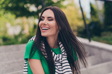 Wall Mural - Photo of positive dreamy girl dressed green top sitting stairs enjoying sunshine smiling outdoors urban town park