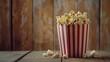A delicious and crispy snack perfect for movie night. The popcorn is served in a red and white striped container and placed on a rustic wooden table.
