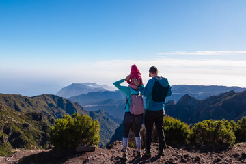Wall Mural - Hiker family with small child looking at scenic view of misty hills and canyon of rugged terrain on Madeira island, Portugal, Europe. Idyllic hiking trail to mountain peak Pico Ruivo. Aerial vista